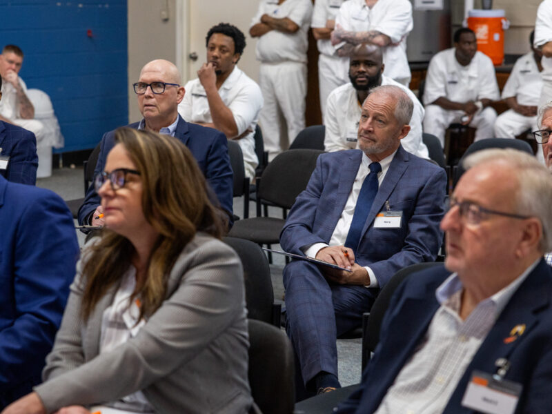 Business professionals and incarcerated participants attentively listening during a Prison Entrepreneurship Program event focused on leadership and mentorship
