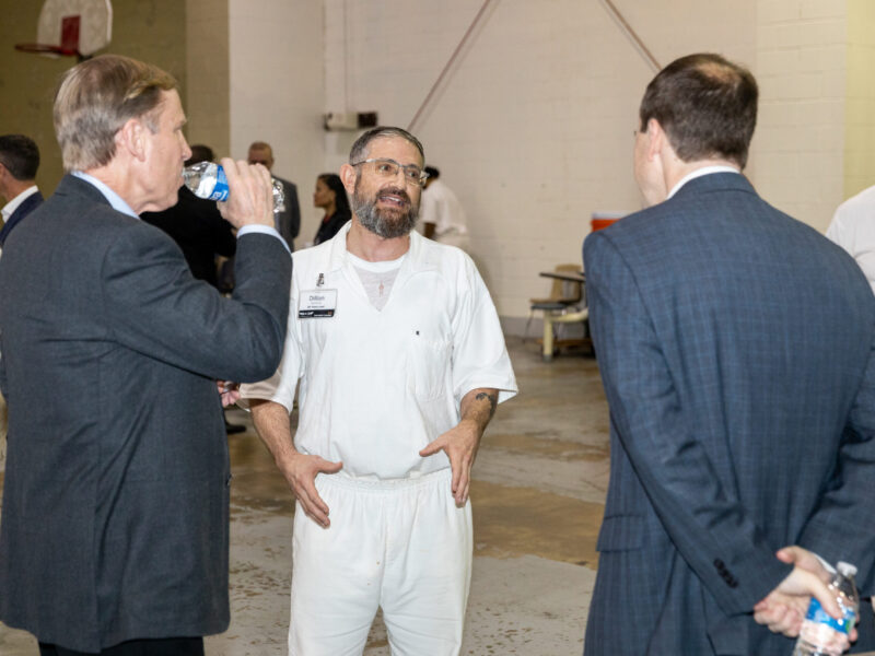 Prison Entrepreneurship Program participant speaks with business leaders during a PEP event focused on mentorship and second chances in a Texas prison gym