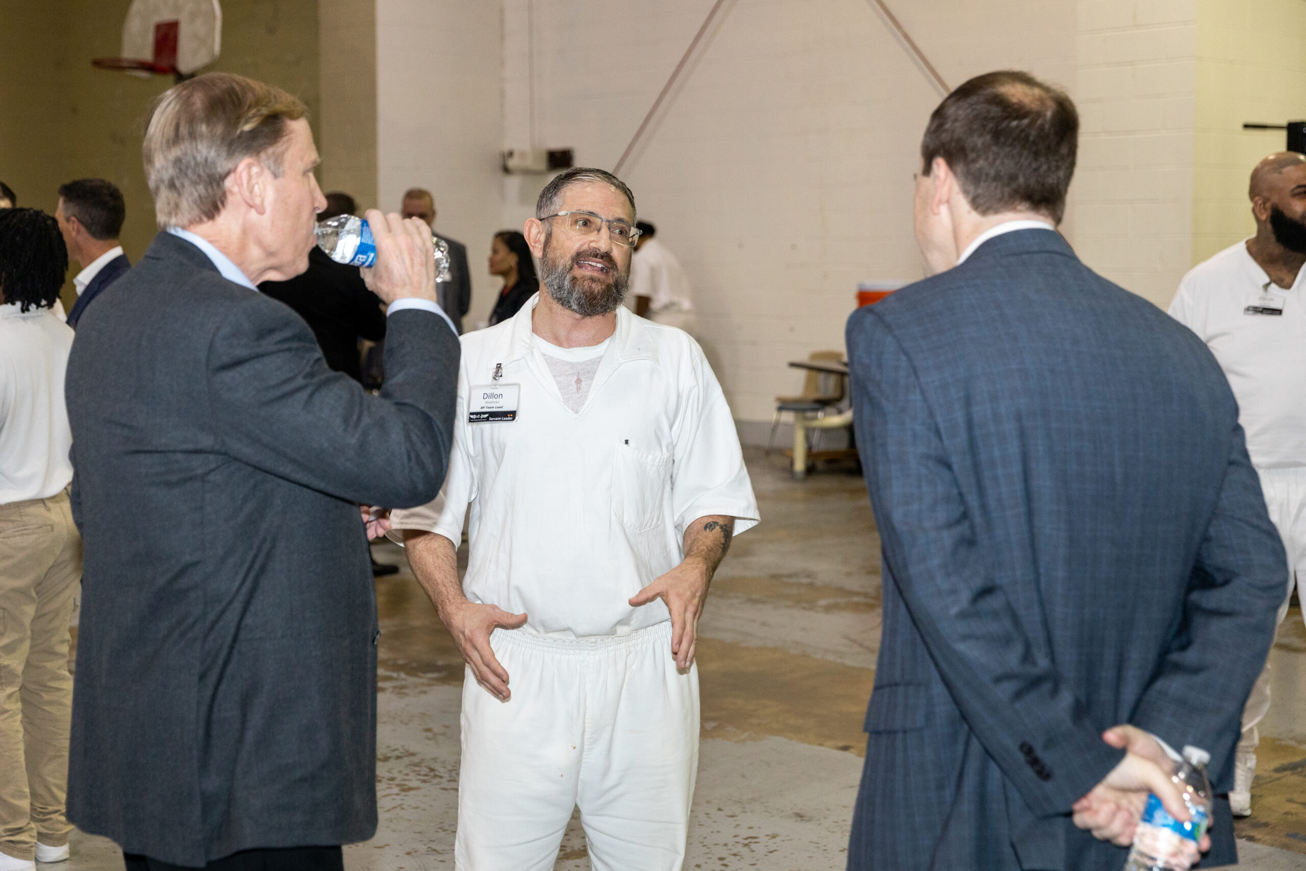 Prison Entrepreneurship Program participant speaks with business leaders during a PEP event focused on mentorship and second chances in a Texas prison gym