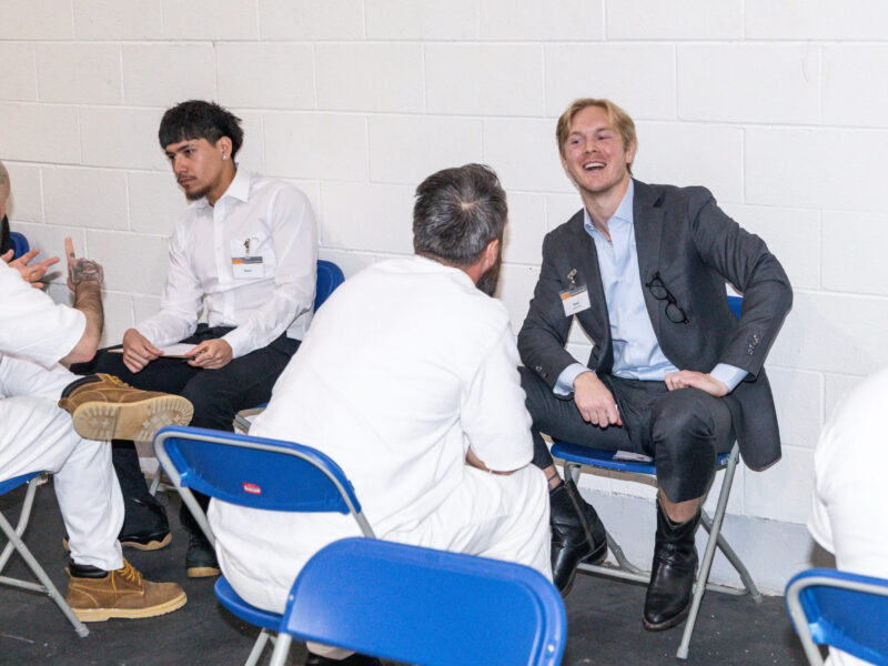 Business professionals and incarcerated participants engage in one-on-one mentoring during a Prison Entrepreneurship Program event inside a Texas prison