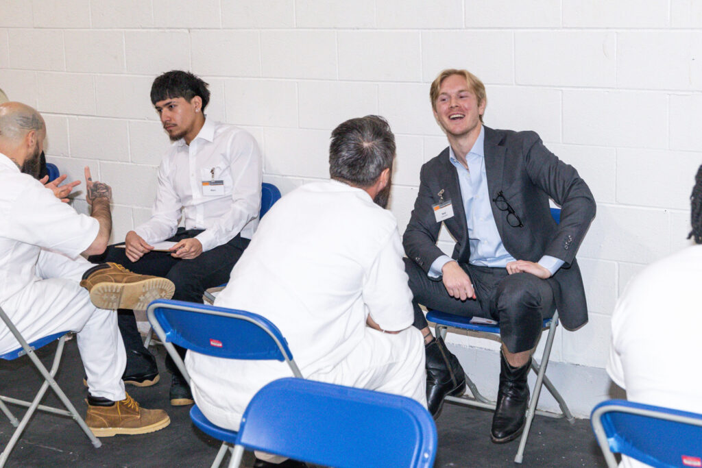 Business professionals and incarcerated participants engage in one-on-one mentoring during a Prison Entrepreneurship Program event inside a Texas prison