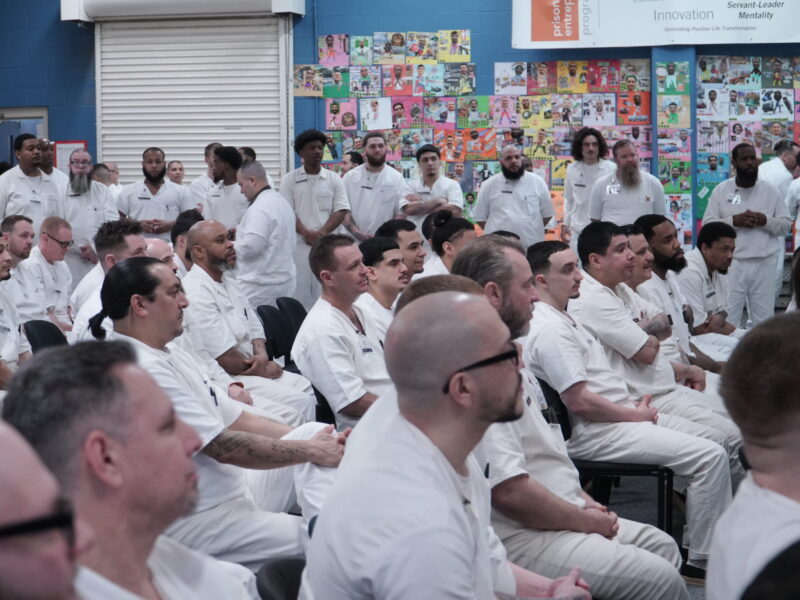 PEP participants seated and standing attentively during a classroom session, with colorful vision boards and program values displayed on the wall