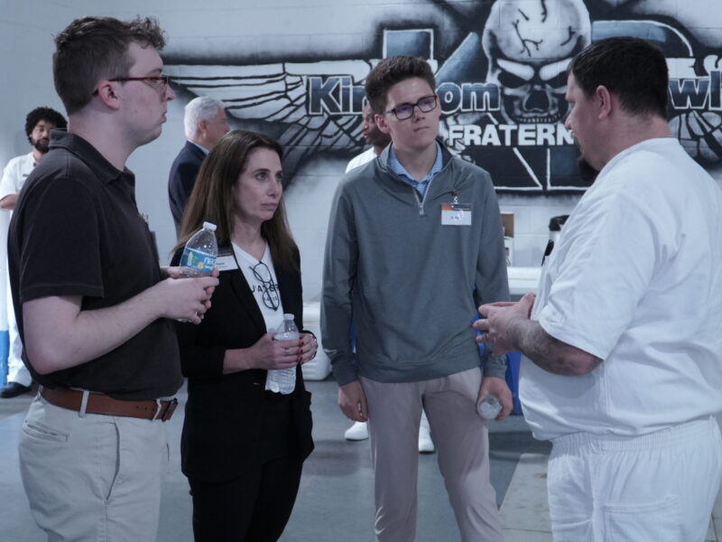 PEP participant discusses his business plan with a group of visiting business professionals during a mentoring event inside prison