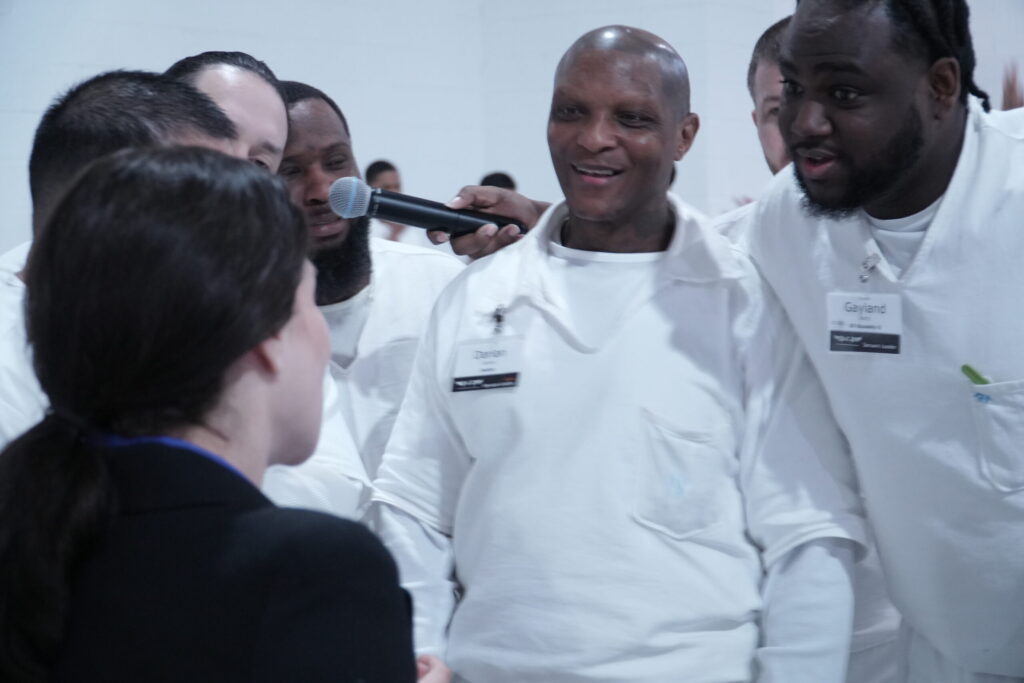 PEP participants engaging with a volunteer during a Q&A session inside prison, smiling and holding a microphone