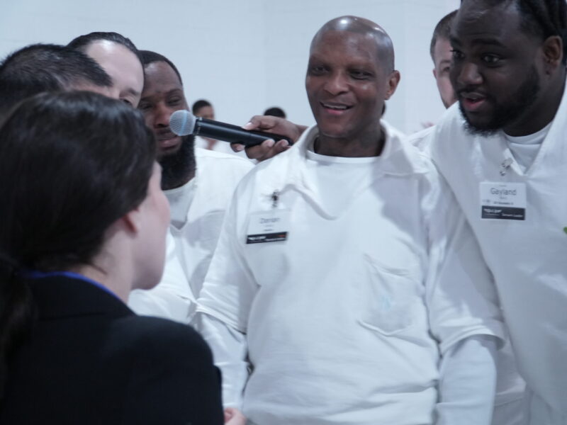 PEP participants engaging with a volunteer during a Q&A session inside prison, smiling and holding a microphone