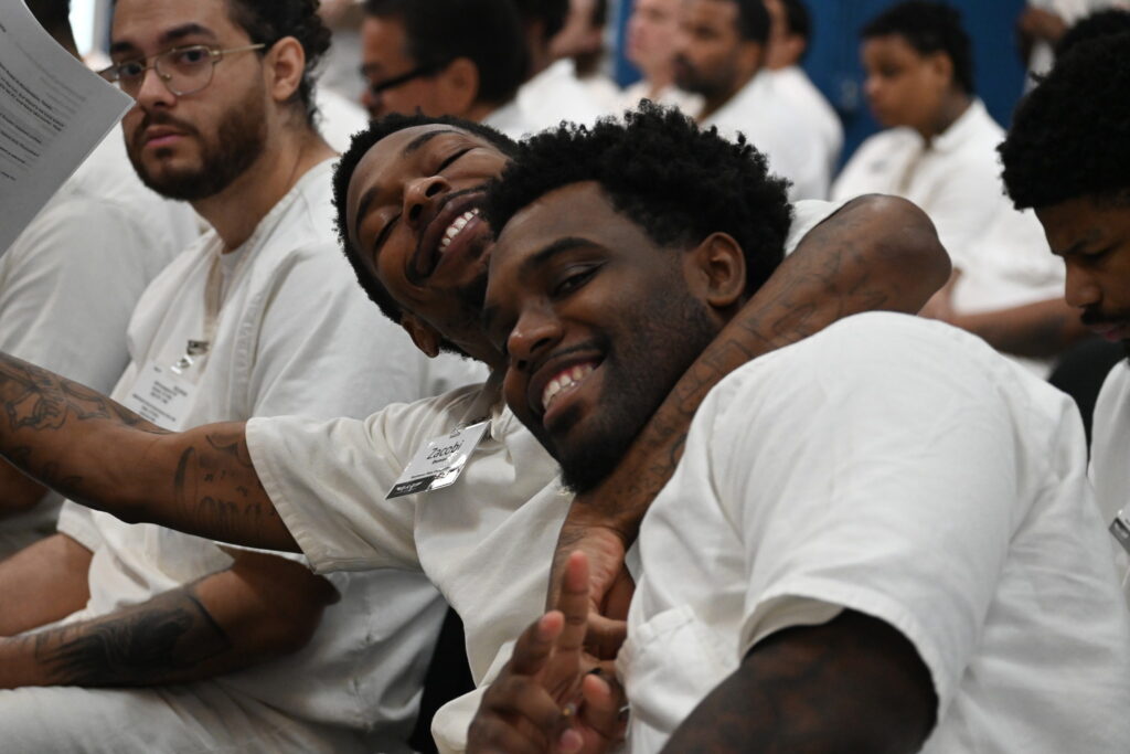 PEP participants smiling and embracing during a Prison Entrepreneurship Program event, showing strong brotherhood and support