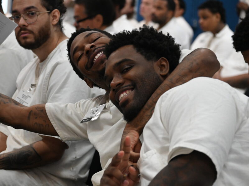 PEP participants smiling and embracing during a Prison Entrepreneurship Program event, showing strong brotherhood and support