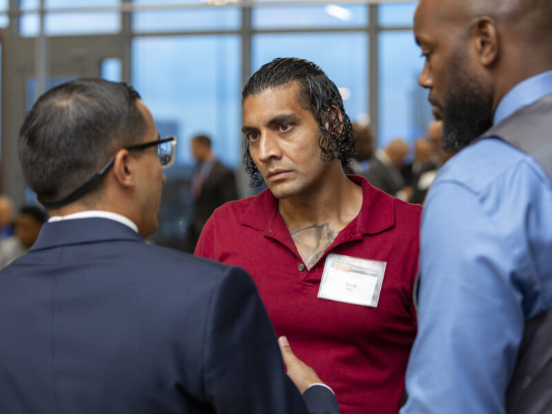 PEP graduate Sean Mall engages in a focused conversation during a Prison Entrepreneurship Program networking event with business executives
