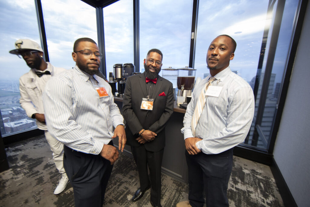 Formerly incarcerated PEP graduates network at a professional event overlooking the Dallas skyline following completion of the Prison Entrepreneurship Program
