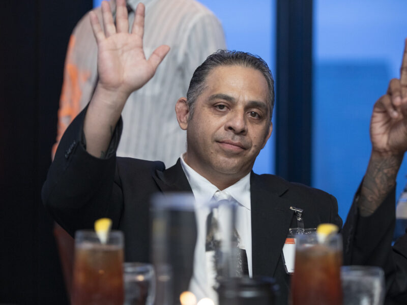 Formerly incarcerated PEP graduate raises hand during a Prison Entrepreneurship Program gala event celebrating transformation and second chances