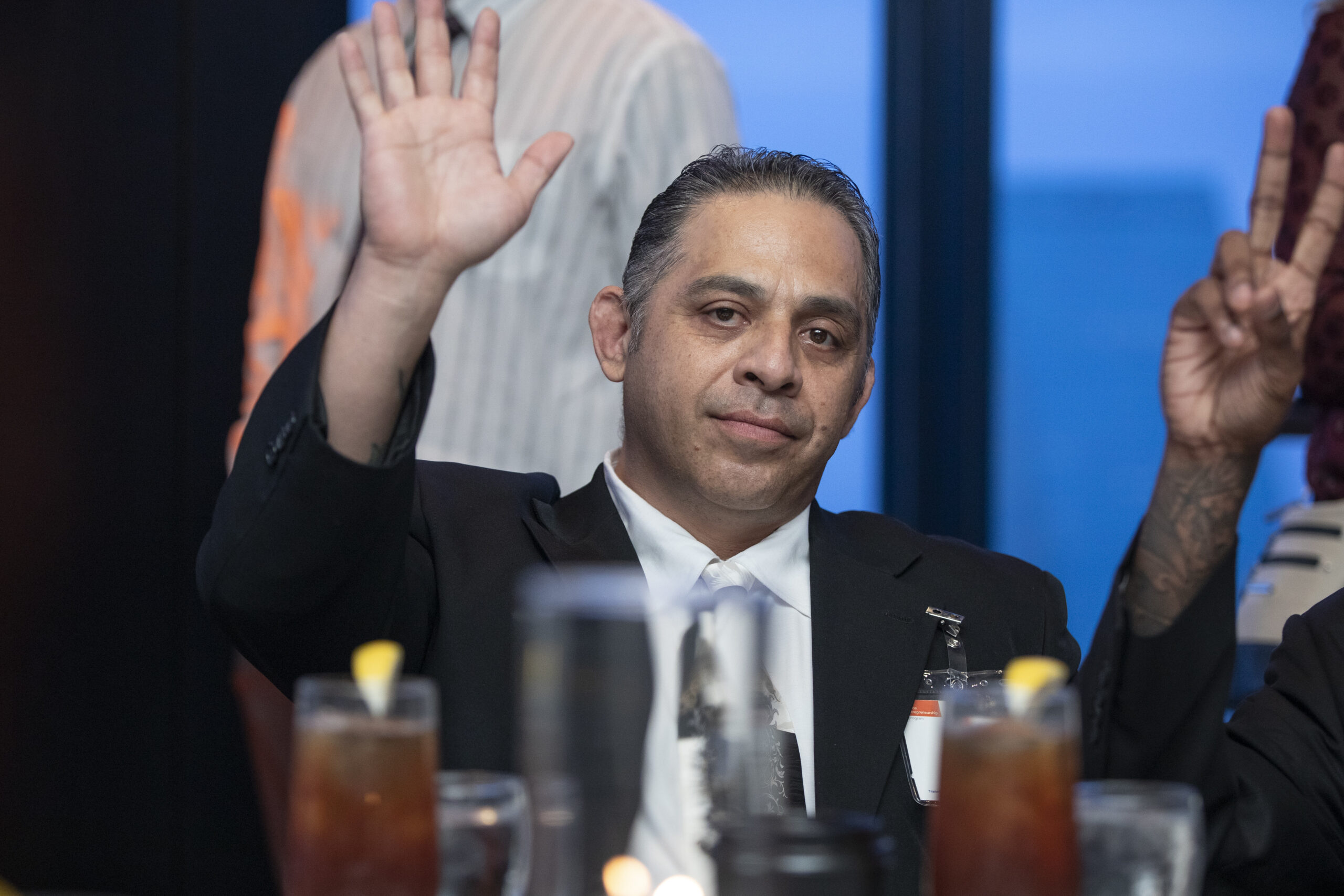Formerly incarcerated PEP graduate raises hand during a Prison Entrepreneurship Program gala event celebrating transformation and second chances