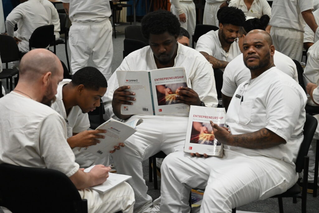 Prison Entrepreneurship Program participants study business textbooks and take notes during a PEP class session on entrepreneurship and leadership