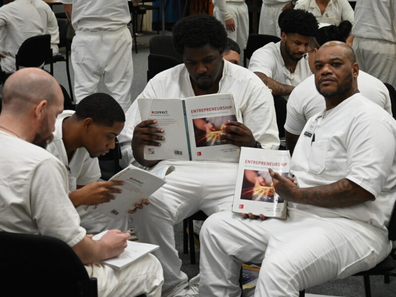 Prison Entrepreneurship Program participants study business textbooks and take notes during a PEP class session on entrepreneurship and leadership