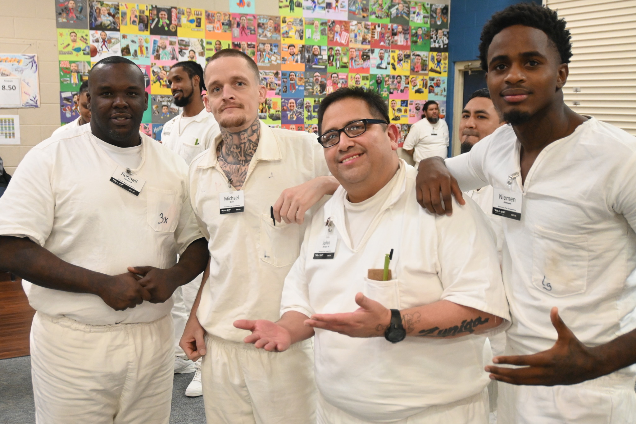 Prison Entrepreneurship Program participants gather and pose in front of colorful artwork during a PEP class session celebrating creativity and community